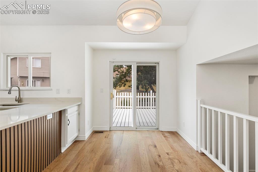 Image 12 of 27: Kitchen with light wood finished floors, white cabinetry, and light counter