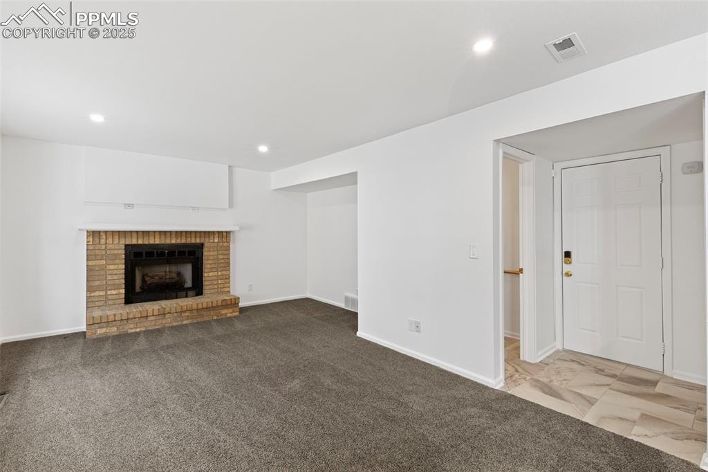 Image 13 of 27: Unfurnished living room featuring recessed lighting, a brick fireplace, and