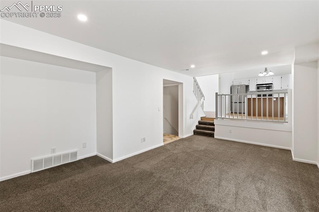 Image 14 of 27: Unfurnished living room featuring dark colored carpet, recessed lighting, a