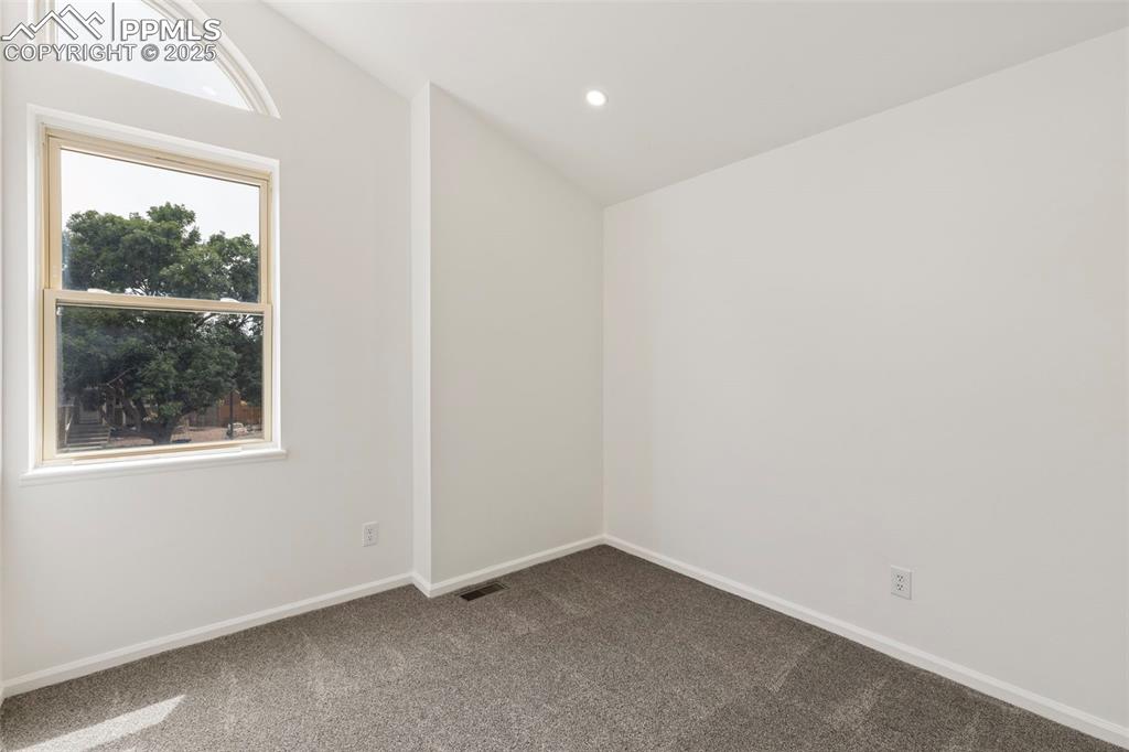 Image 16 of 27: Spare room with vaulted ceiling, dark carpet, and recessed lighting