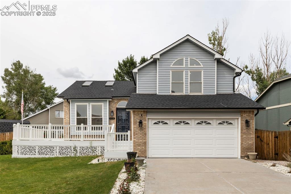 Image 2 of 27: View of front of home with concrete driveway, a garage, brick siding, a shi