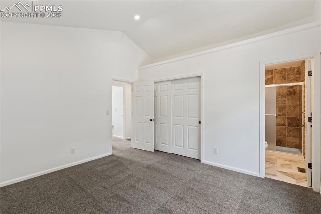 Image 20 of 27: Unfurnished bedroom with lofted ceiling, carpet floors, a closet, and ensui