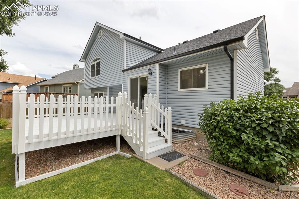 Image 26 of 27: Rear view of property featuring a wooden deck and roof with shingles