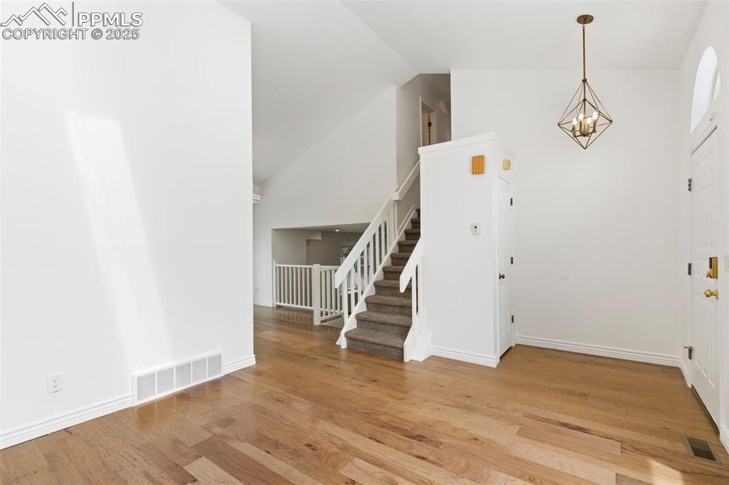 Image 7 of 27: Entrance foyer with stairway, light wood-type flooring, a chandelier, and h