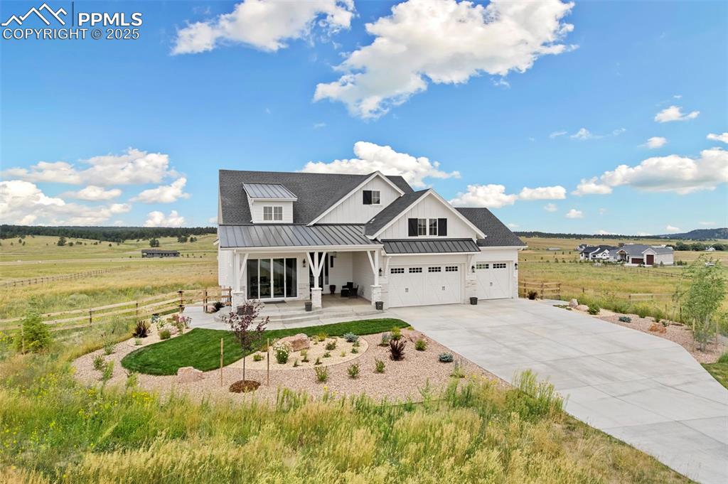 Caption: Modern inspired farmhouse featuring a standing seam roof, a porch, a metal roof, concrete driveway, 