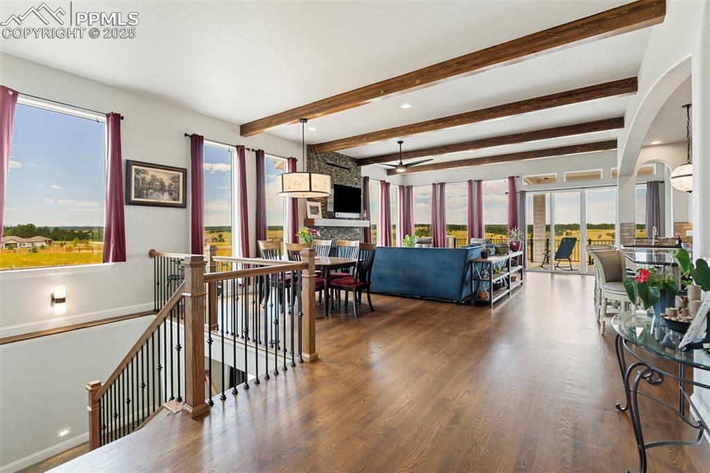 Image 12 of 50: Living room with beamed ceiling, wood finished floors, arched walkways, and
