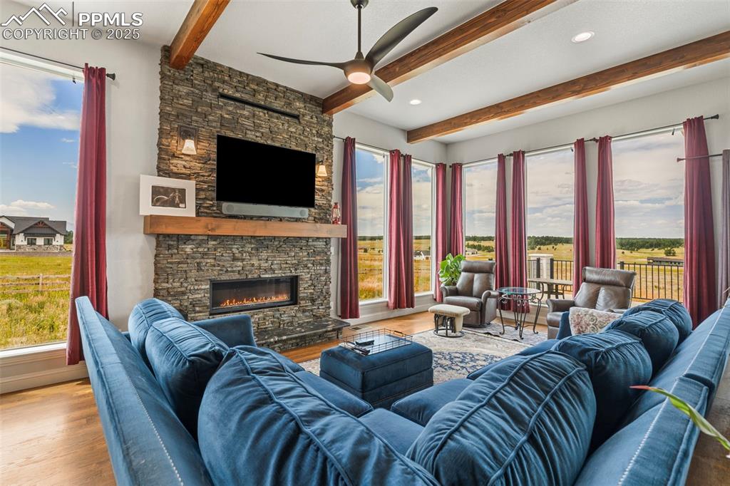 Image 13 of 50: Living area with beam ceiling, wood finished floors, a fireplace, ceiling f