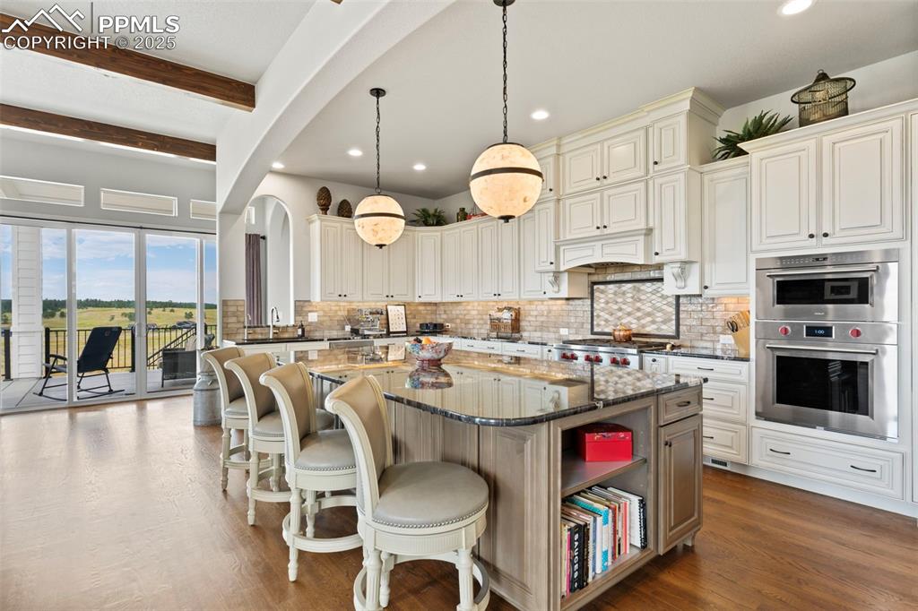 Image 19 of 50: Kitchen with dark stone counters, a center island, decorative light fixture