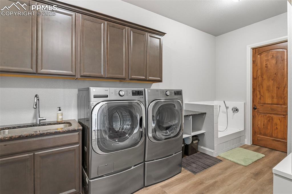 Image 24 of 50: Washroom with light wood finished floors, washer and clothes dryer, and cab