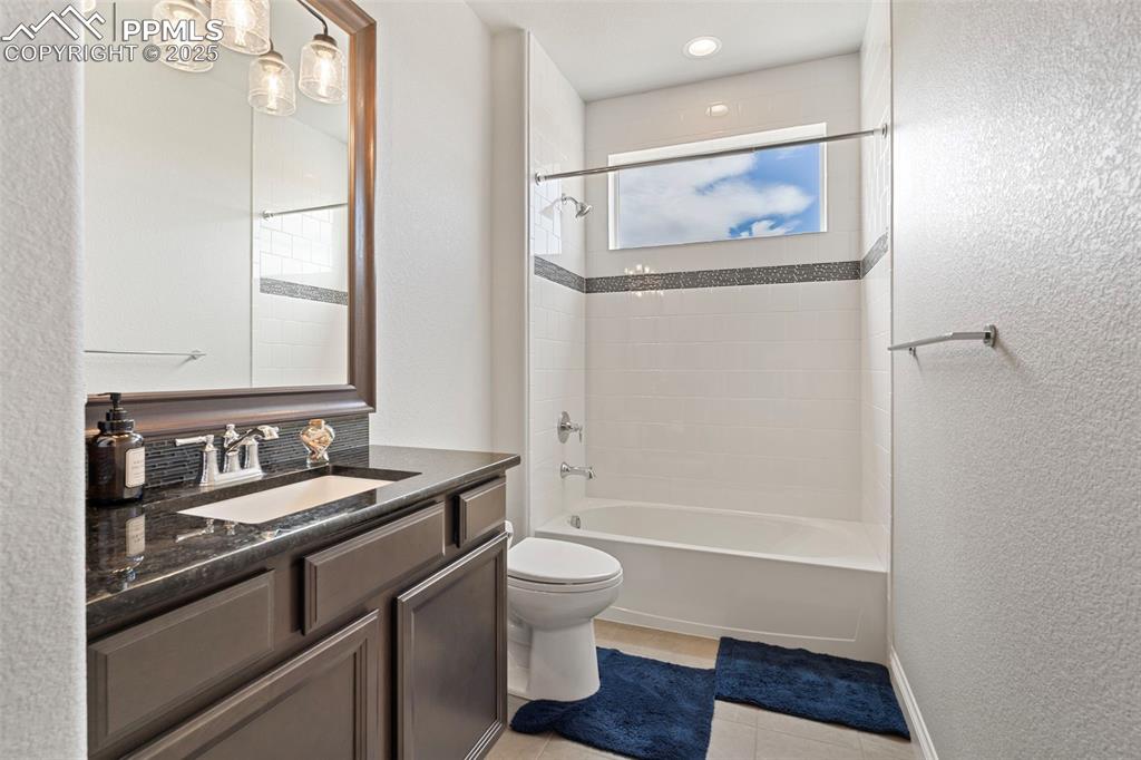 Image 26 of 50: Bathroom with a textured wall, shower / bath combination, vanity, and light