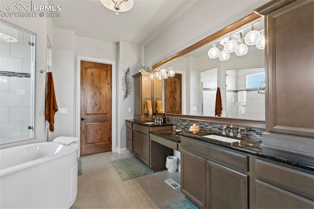 Image 32 of 50: Full bathroom with a soaking tub, tiled shower, decorative backsplash, and