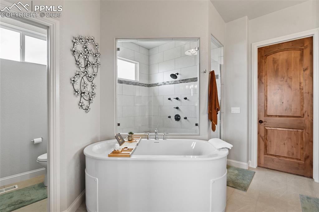 Image 33 of 50: Bathroom with a soaking tub, light tile patterned floors, and tiled shower