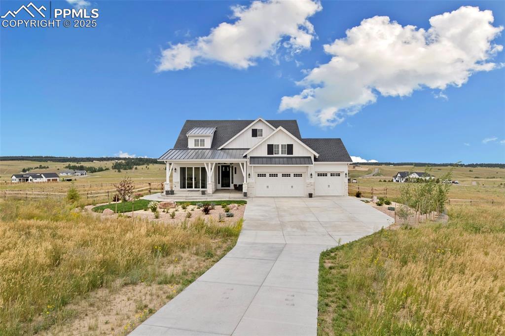 Image 5 of 50: Modern farmhouse style home featuring a standing seam roof, a porch, a meta