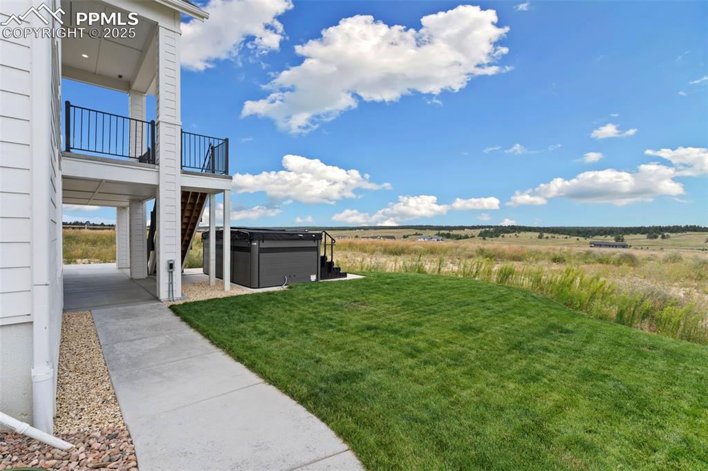 Image 50 of 50: View of grassy yard with a patio, a hot tub, and a view of countryside