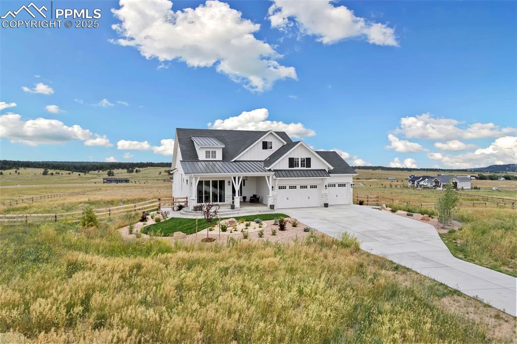 Image 6 of 50: Modern inspired farmhouse featuring a rural view, a standing seam roof, a m