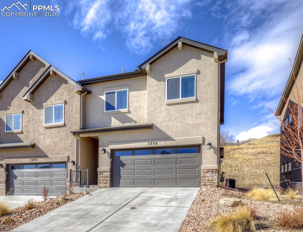 Caption: Traditional-style house with stone siding, stucco siding, concrete driveway, and an attached garage
