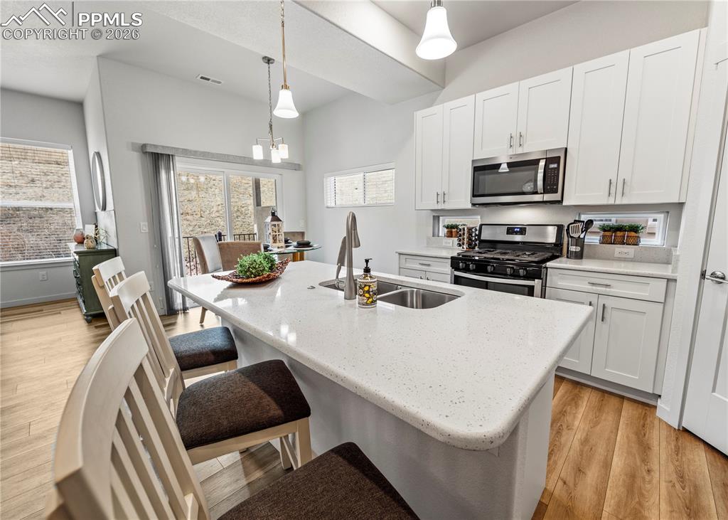 Image 10 of 46: Kitchen with light wood-style floors, stainless steel appliances, white cab