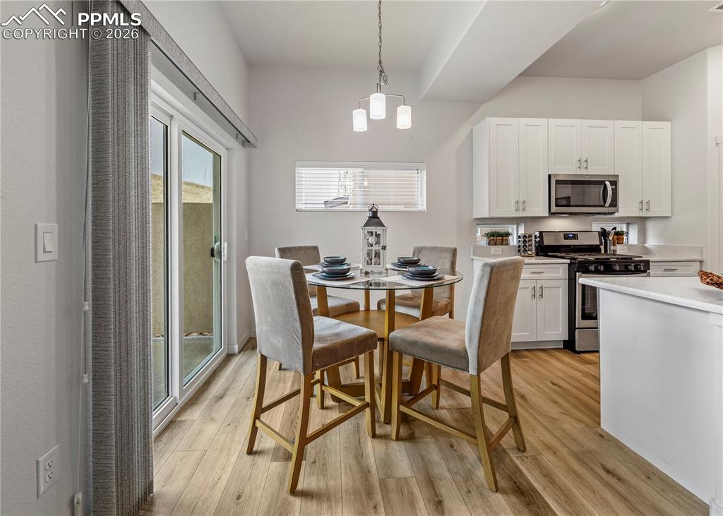 Image 14 of 46: Dining room with light wood-style flooring and suspended lighting