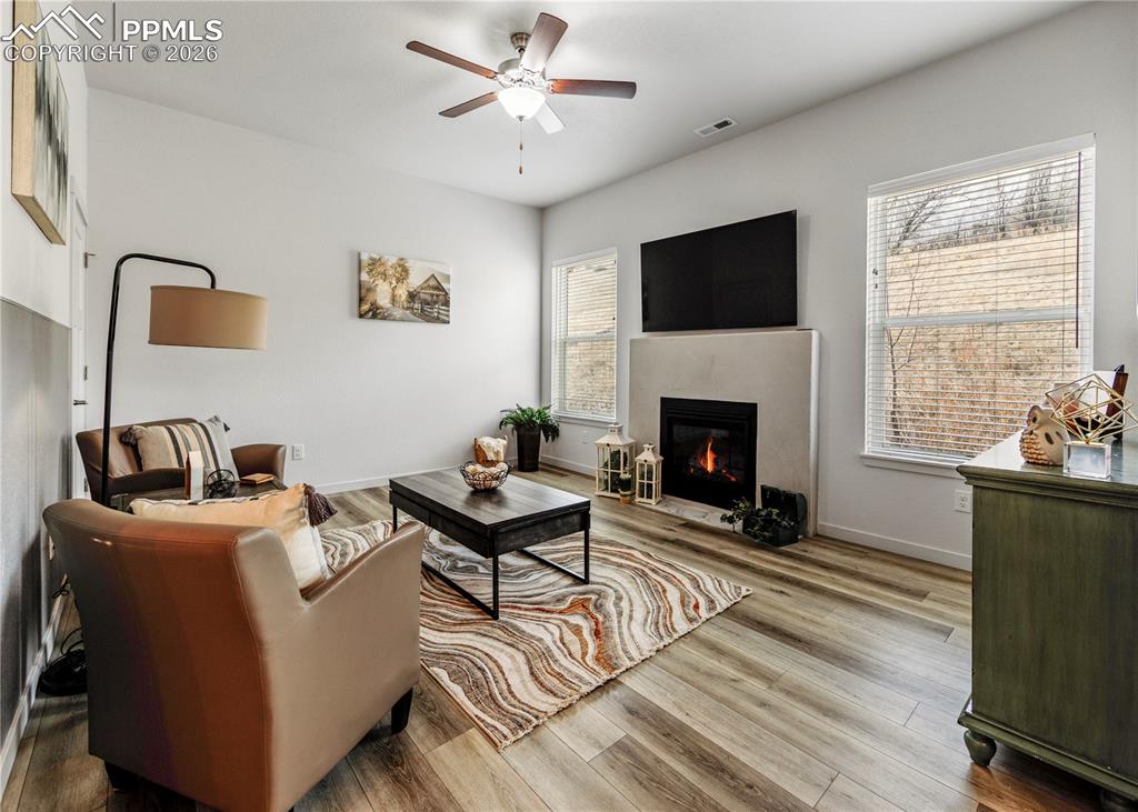 Image 16 of 46: Living room with light wood-style floors, ceiling fan, and a glass covered 