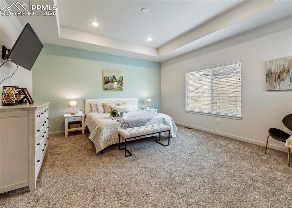 Image 22 of 46: Bedroom featuring light colored carpet, a tray ceiling, and recessed lighti