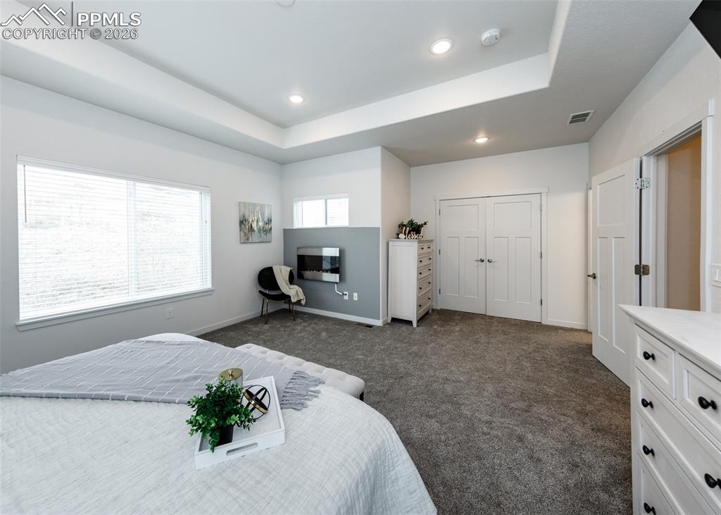 Image 27 of 46: Bedroom with a raised ceiling, dark colored carpet, and recessed lighting