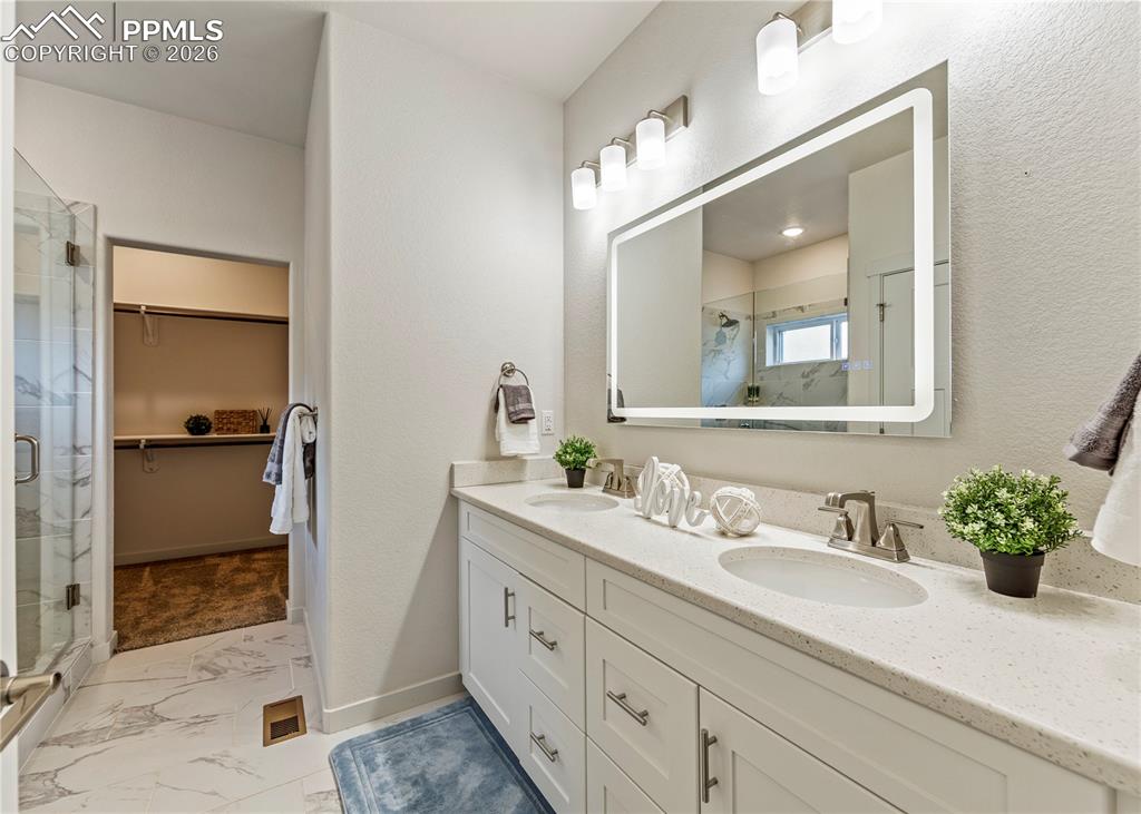 Image 28 of 46: Full bathroom with a spacious closet, double vanity, a marble finish shower