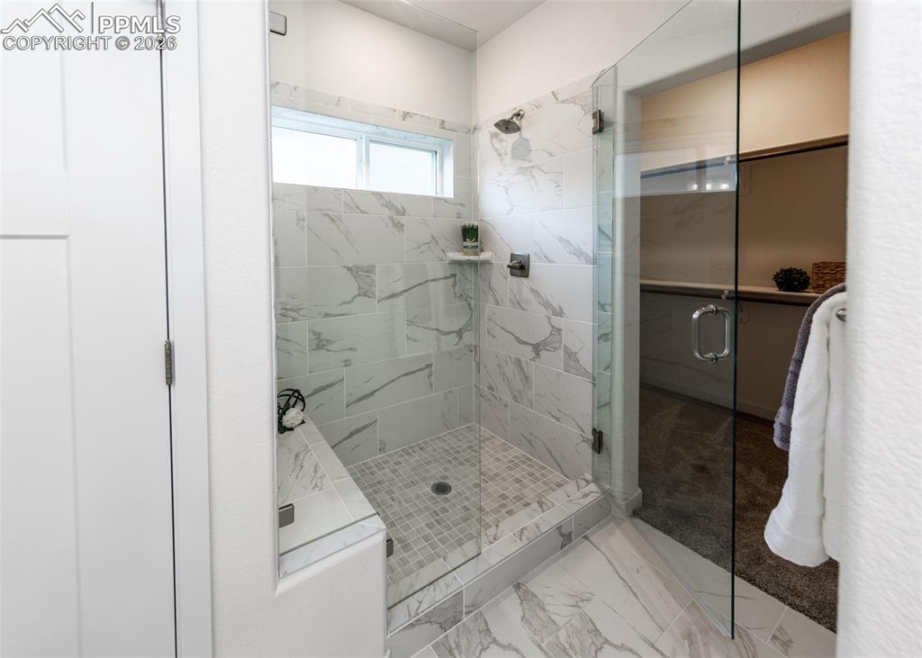 Image 30 of 46: Bathroom featuring a marble finish shower and light marble finish floors
