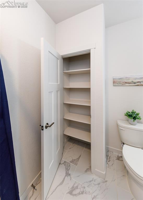 Image 39 of 46: Bathroom featuring toilet and light marble finish floors