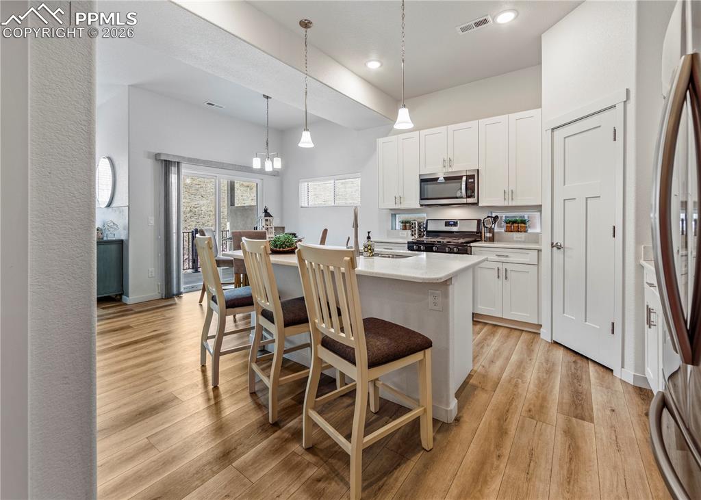Image 8 of 46: Kitchen featuring stainless steel appliances, white cabinetry, light wood-t