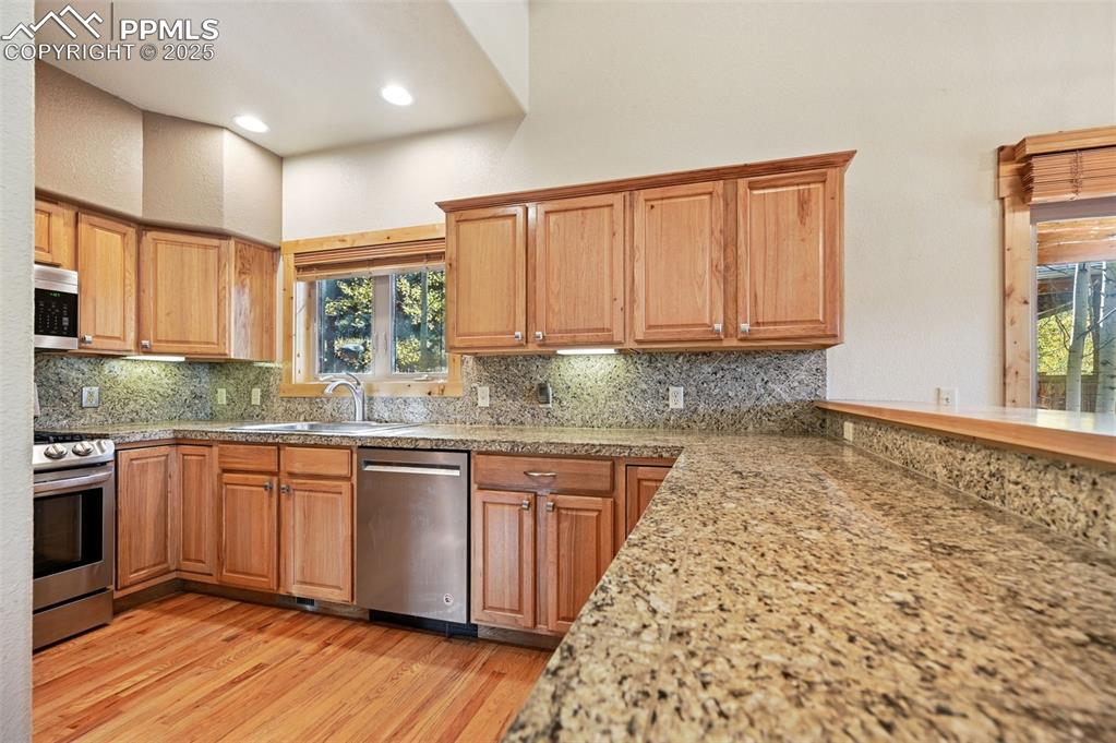 Image 18 of 42: Kitchen with appliances with stainless steel finishes, light wood-style flo