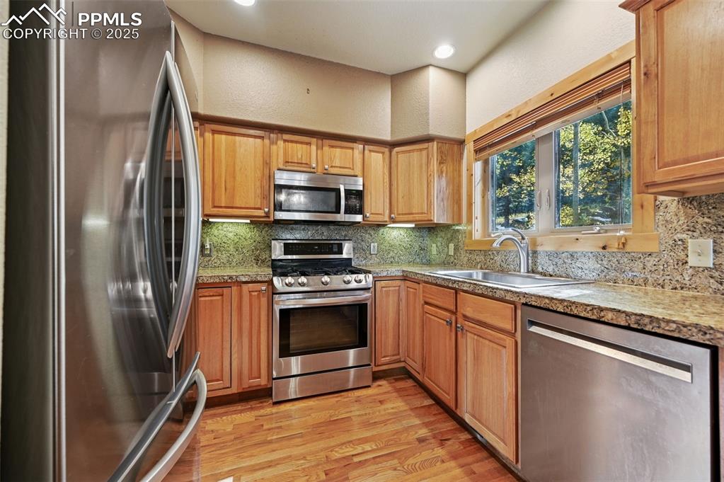 Image 19 of 42: Kitchen with stainless steel appliances, a textured wall, light wood-type f