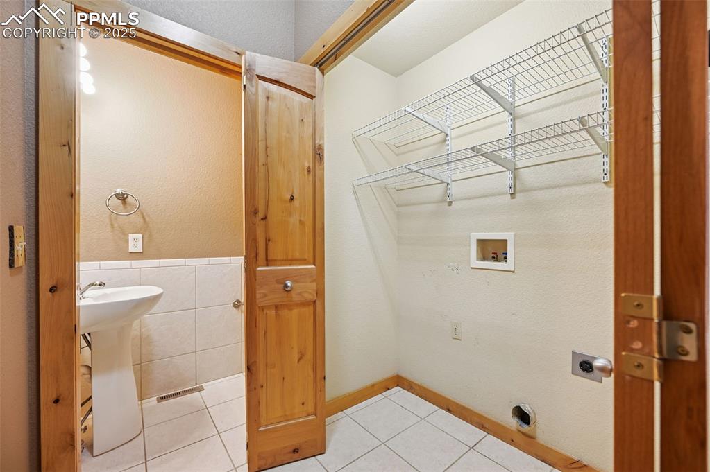 Image 21 of 42: Washroom featuring light tile patterned floors, washer hookup, tile walls, 