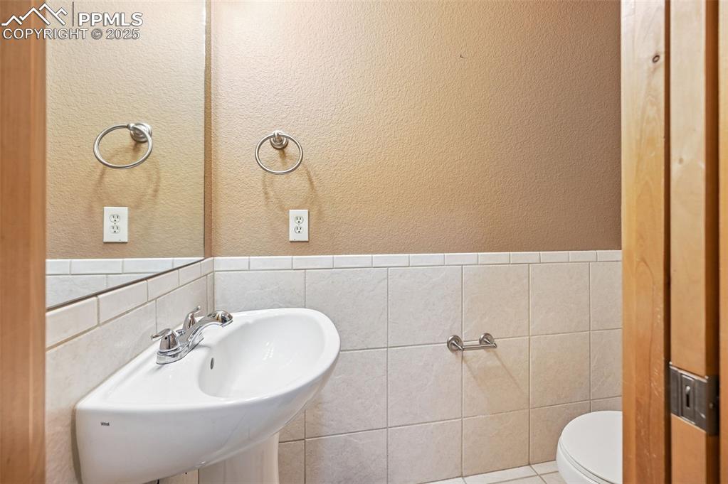 Image 22 of 42: Bathroom featuring a textured wall, tile walls, a wainscoted wall, and tile
