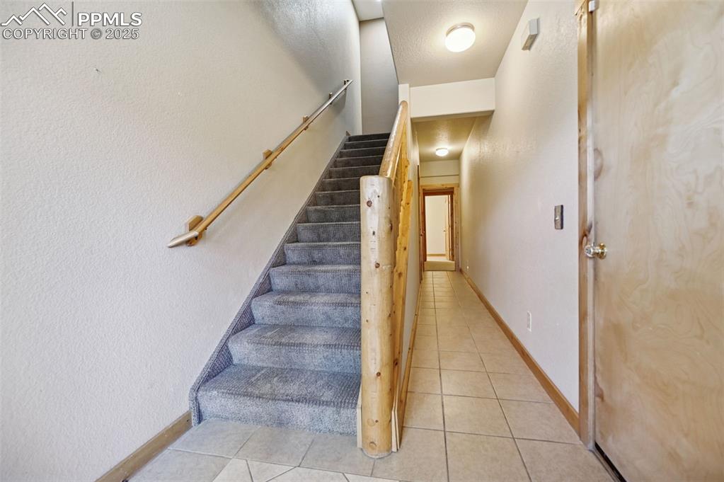 Image 4 of 42: Stairway with tile patterned floors and a textured wall