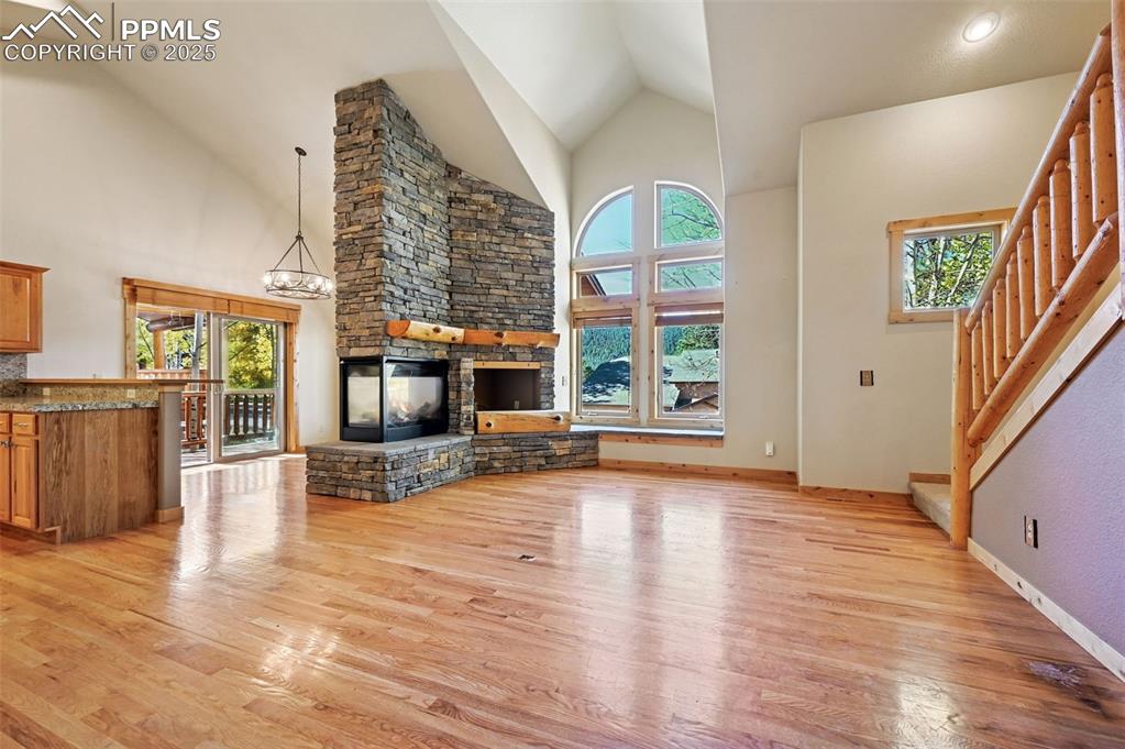 Image 9 of 42: Unfurnished living room with high vaulted ceiling, light wood-style floorin