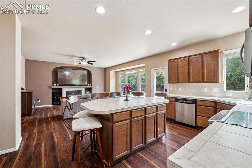 Image 11 of 46: Kitchen featuring tile counters, a fireplace, dark wood finished floors, a