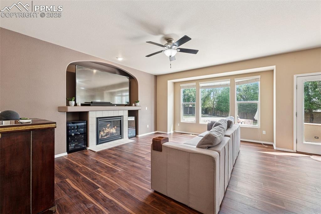 Image 12 of 46: Living room featuring wood finished floors, wine coolers, a gas fireplace,