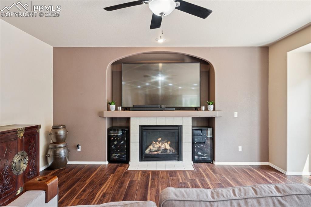 Image 13 of 46: Living area with wood finished floors, a fireplace, and wine cooler