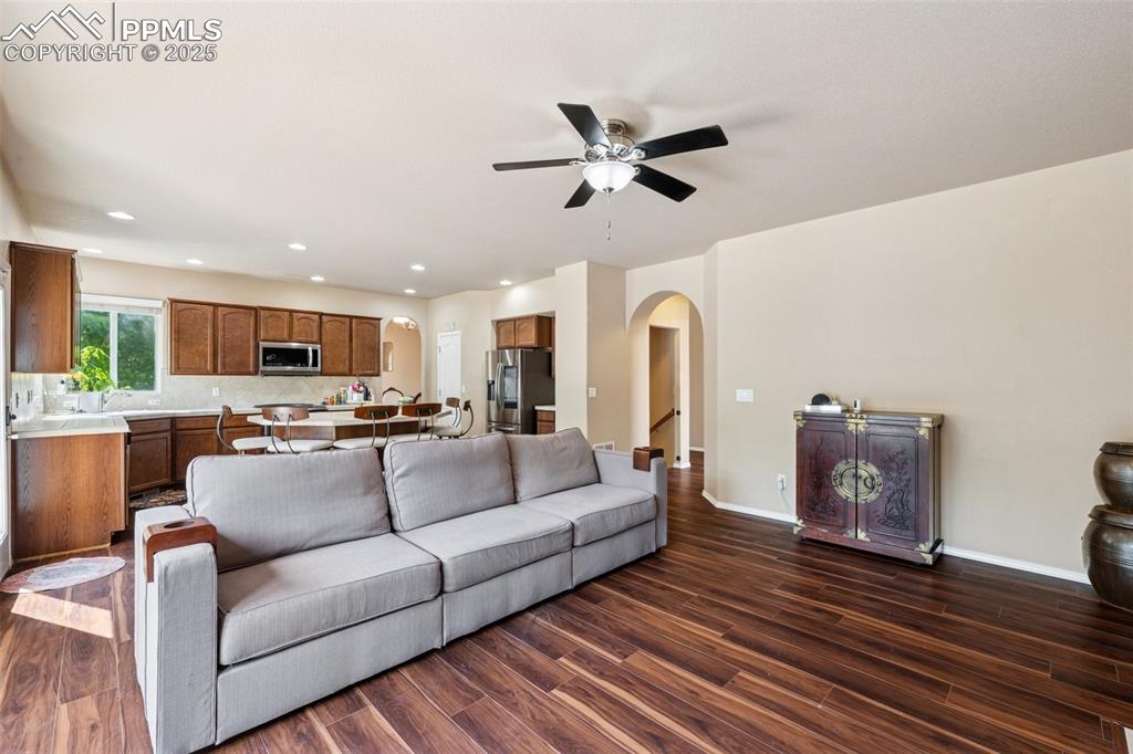 Image 14 of 46: Living room featuring dark wood-style flooring, arched walkways, recessed l