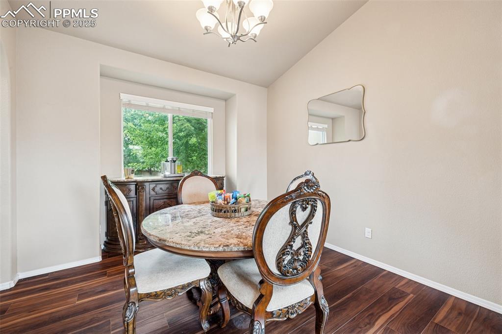 Image 15 of 46: Dining area with vaulted ceiling, dark wood-style floors, and a chandelier