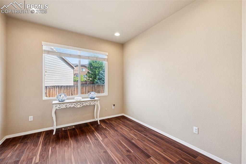 Image 18 of 46: Empty room with dark wood-style floors and recessed lighting