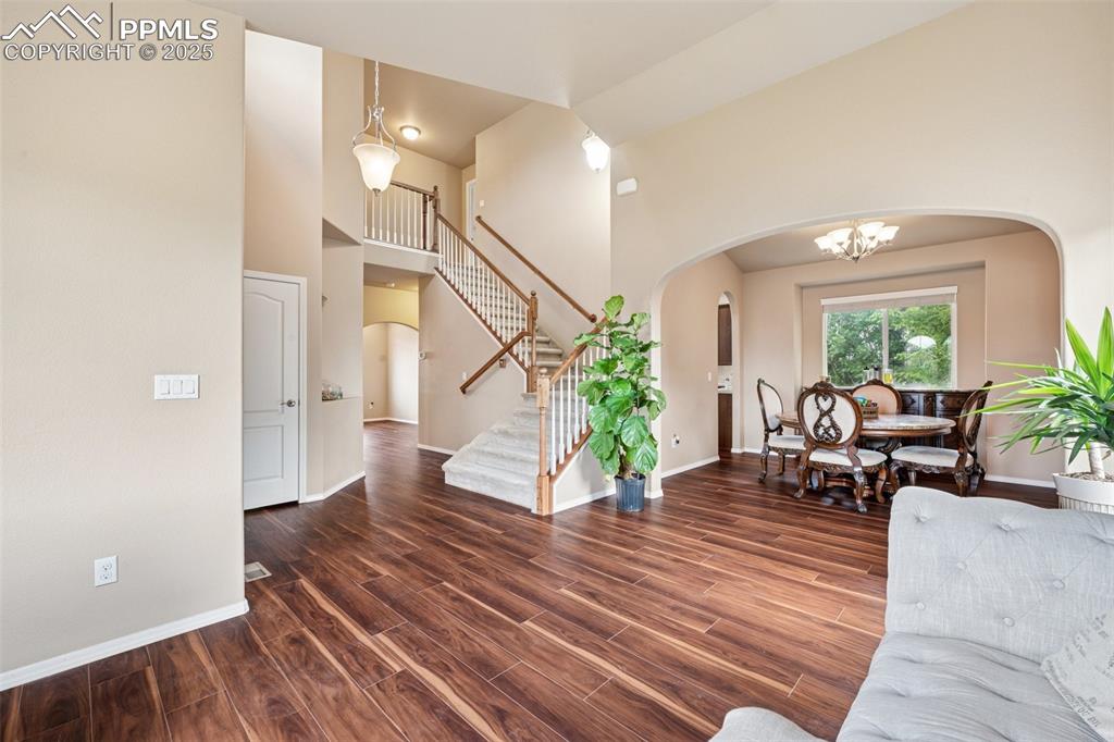 Image 21 of 46: Living room featuring arched walkways, a towering ceiling, wood finished fl