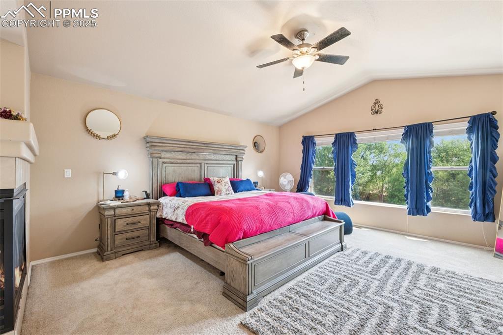 Image 22 of 46: Carpeted primary suite featuring a fireplace, vaulted ceilings, sitting are