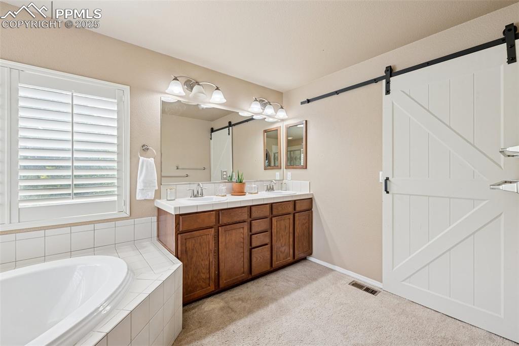 Image 26 of 46: Bathroom featuring double vanity and a bath