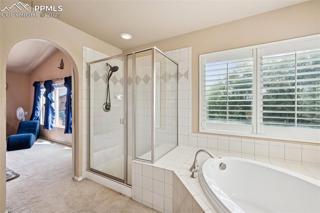 Image 27 of 46: Bathroom featuring a bath, a stall shower, and vaulted ceiling