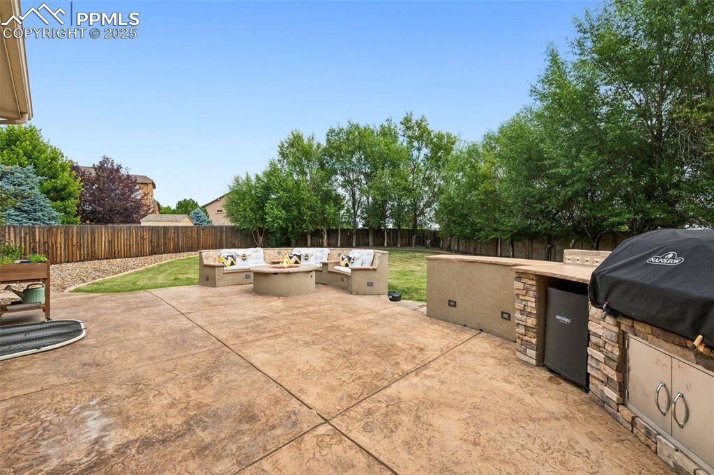 Image 4 of 46: Fenced backyard with area for grilling, a patio, and an outdoor fire pit
