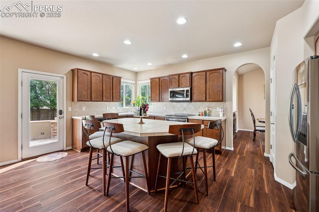 Image 9 of 46: Kitchen with tile counters, arched walkways, stainless steel appliances, da