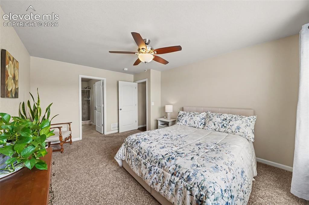 Image 14 of 32: Spacious main-level primary bedroom featuring plush carpeting, a peaceful a