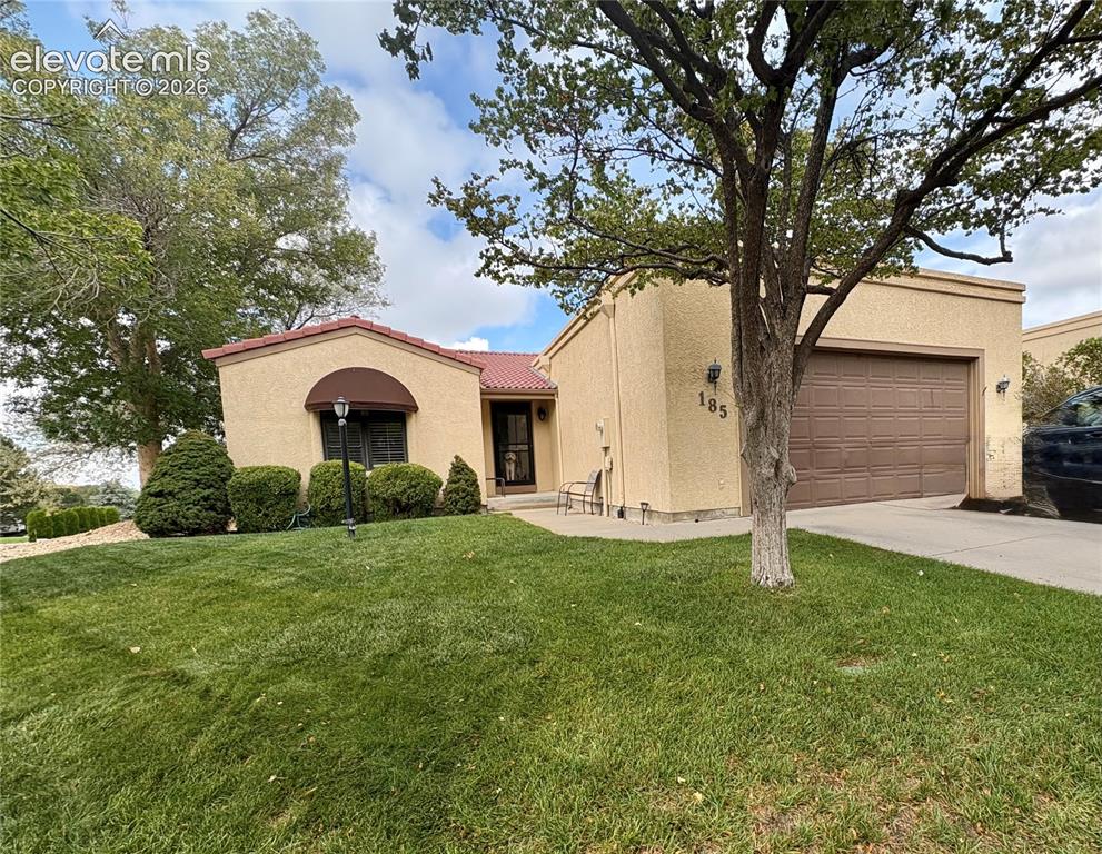 Image 1 of 28: Stucco exterior, red tile roof accent, attached garage, well-maintained law