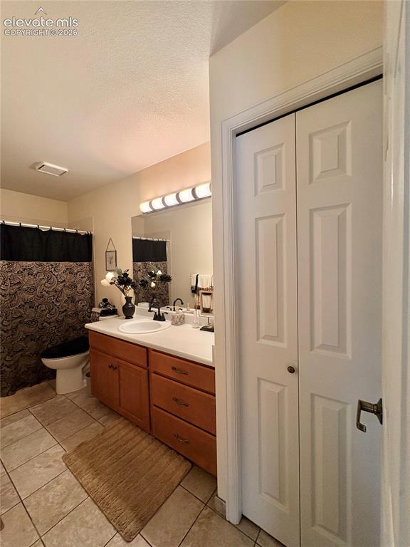 Image 11 of 28: White panel bi-fold doors, tile flooring, wood-finish vanity with built-in